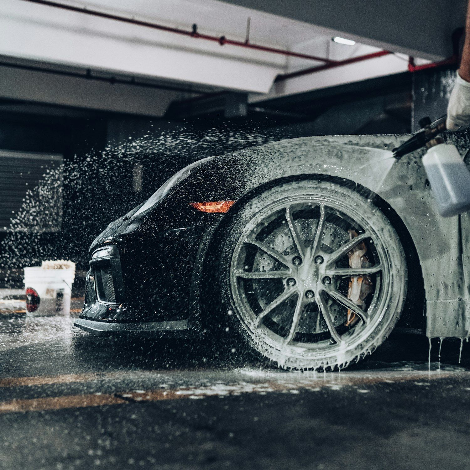 A black sports car being foam-washed at Apex Auto Detailing